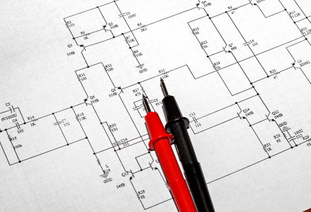 Red and black probes against the background of an electronic circuit diagramの写真素材
