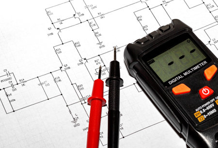 Red and black probes and a digital multimeter against the background of an electronic circuit...