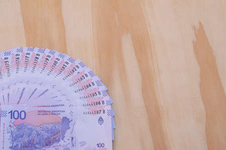 Argentine banknotes of 100 pesos, taruca, of correlative numbering. With a wooden background.の写真素材