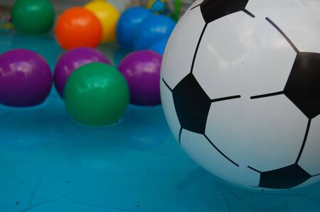 floated soccer ball and bunch of colorful small balls in water