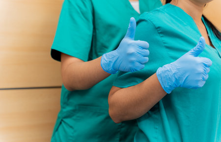 Close-up of the hands of two female doctors with thumbs up