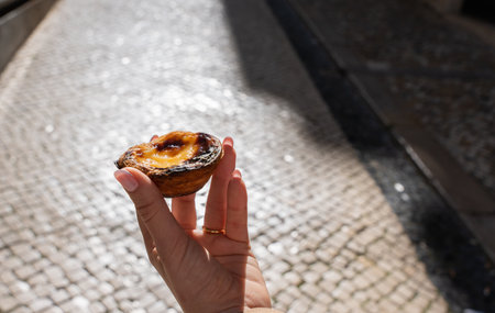 Hand of a woman with the traditional sweet dessert of Portugal. Belem Cake.の写真素材