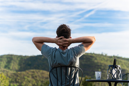 Young man relaxing in the morning with green mountainous landscape viewsの写真素材