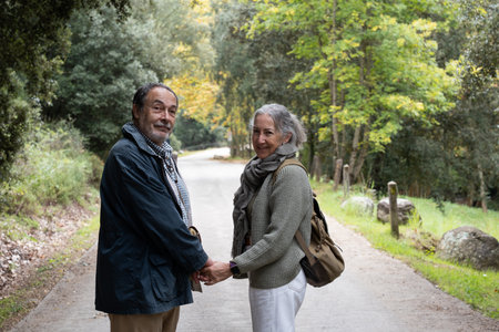Close up of senior couple holding hands walking on nature pathの写真素材