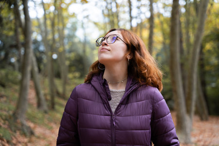 Woman smiling and looking up in a peaceful autumn forest