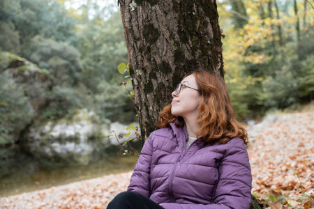 Woman relaxing in autumn forest contemplating natureの写真素材