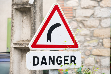 Road danger warning sign indicating a curveの写真素材