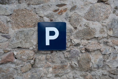 Blue parking sign showing p symbol on stone wallの写真素材