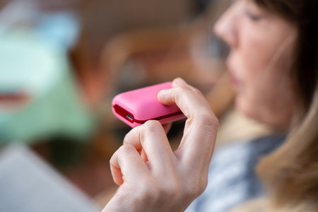 Woman holding a pink electronic cigarette while exhaling vaporの写真素材