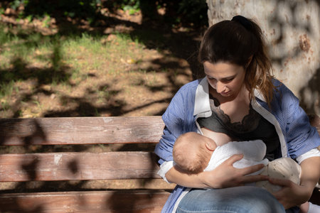 Mother breastfeeding a baby outdoors, creating a nourishing bondの写真素材