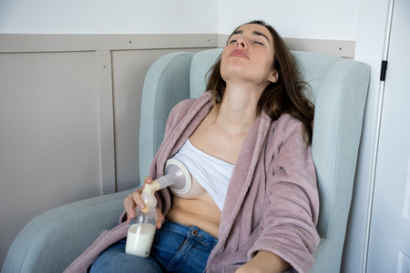 woman with a manual breast pump sitting in the armchair looks exhausted