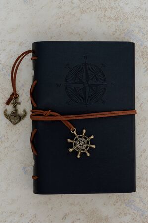 Vintage black notebook with travel theme with gold anchor, ship's helm and compass print.の写真素材