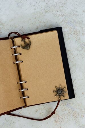 Empty yellow page of a vintage black notepad with travel theme with gold anchor and ship rudder.の写真素材