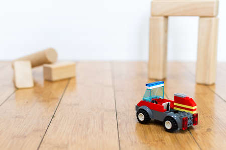 Red toy with wooden blocks on a wooden floor and white background. Building toys simulating the construction of a house.の写真素材