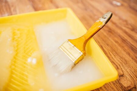 Paintbrush and glue container on concrete surface. Composition tools for home repair and interior renovation indoors.の写真素材