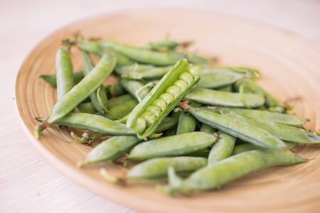 Green peas in white bowl on wooden background, top view.の写真素材