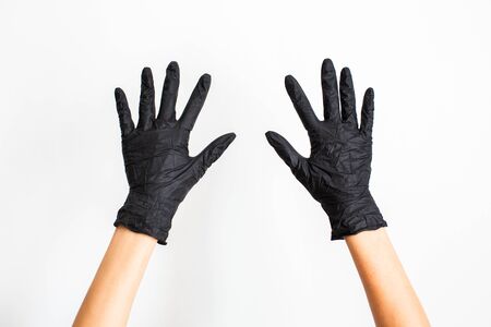 A hand wearing black glove with spread fingers on a white background.の写真素材