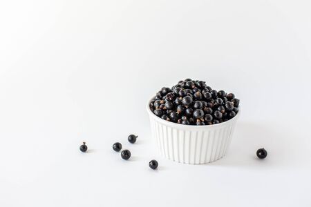 Ripe black currant or blueberries in a small white Cup on a white background. Black currant harvest. Healthy food. vegetarian food.の写真素材