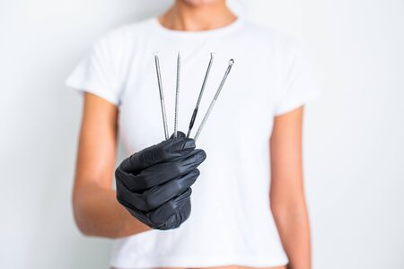 Tools for removing acne. Tools of the cosmetologist for problem skin in woman's hand in black glove