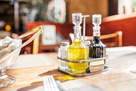 A set of olive oil with soy sauce and sugar bowl on a table in the cafe in a sunrays.の写真素材