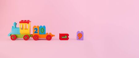 Colorful toy train isolated on pink background with dropped numbers 1 and 9 symbolizes outgoing 2019 year with place for text.の写真素材