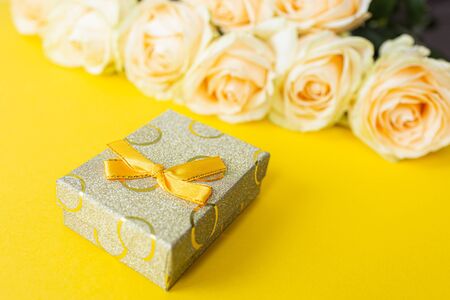 Gift box and white roses on yellow background from above, flat lay frameの写真素材