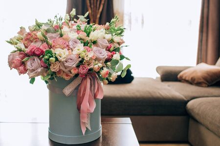 Modern bouquet of flowers in blue round box on a wooden table. Beautiful floral arrangement in a hat box. Flowers bouquet in headboxの写真素材