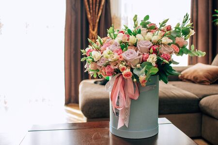 Modern bouquet of flowers in blue round box on a wooden table. Beautiful floral arrangement in a hat box. Flowers bouquet in headbox.の写真素材