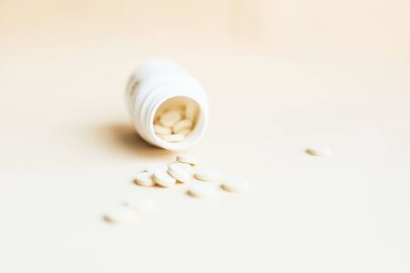 Scattered pills and open container on light background. Vitamins and remedy