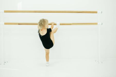 Little ballerina girl in black. Adorable child dancing classical ballet in a white studio. Children dance. Kids performing. Young gifted dancer in a class. Preschool kid taking art lessons.の写真素材