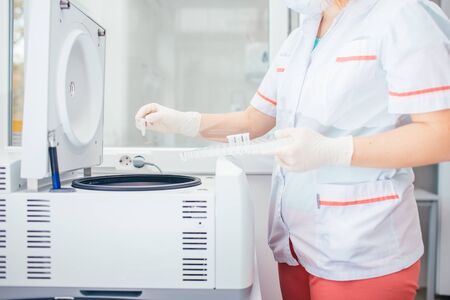 Female lab technician refills a centrifuge machine in the medical or scientific laboratory.