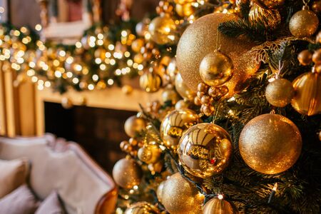 Christmas background with illuminated fir tree with golden decpration and fireplace in living room. Cozy holiday home, close upの写真素材
