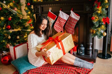 Christmas, winter, happiness concept - smiling woman holding a gift against the background of the...