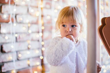 Little girl staying near carousel Merry-go-round with lights on a background