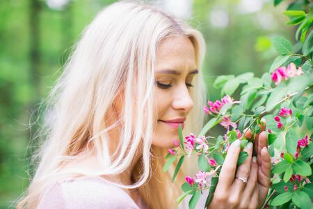 Young Woman Enjoying Smelling Pink Flowers