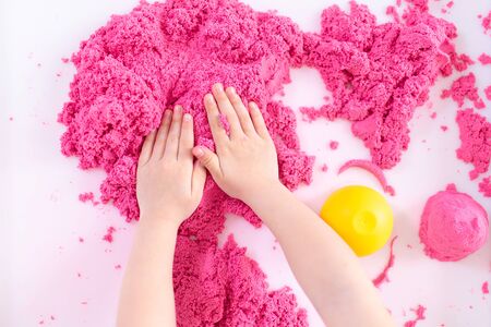 Pink magic sand in a kids hands on a white background close up. Early sensory education. Preparing for School. Development.の写真素材