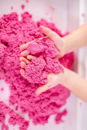 Pink magic sand in a kids hands on a white background close up. Early sensory education. Preparing for School. Development.の写真素材