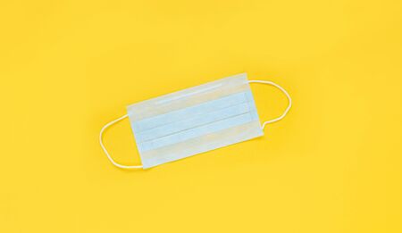 Medical mask on the yellow background, top view. Surgical masks flat lay. Coronavirus protection. Stop Covid-19. Hygiene and healthcare themeの写真素材