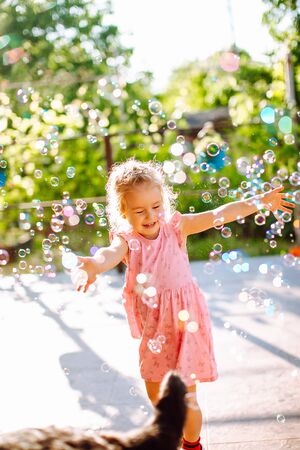 Little blonde girl catching a soap bubbles. Happy childhood, summer holiday conceptの写真素材