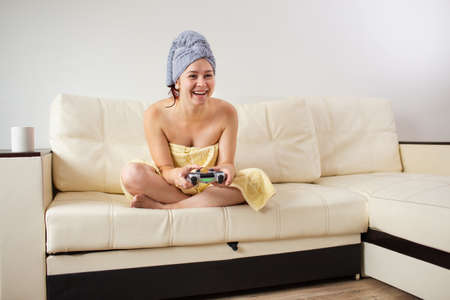 Girl gamer plays with a wireless gamepad while looking at the screen in front of her. Young woman...