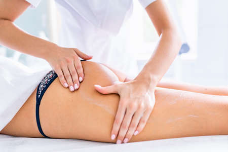Legs and buttocks massage to reduce cellulite and preserve an healthy look. Womans hands applying...