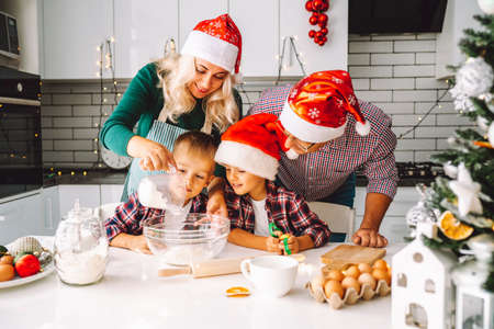 Family of two twins boys and age parents preparing cookies for Xmas eve in light kitchen.の写真素材
