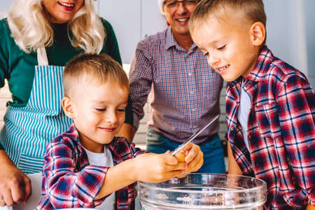 Family of two twins boys and age parents preparing cookies for Xmas eve in light kitchen.の写真素材
