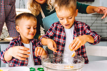 Happy family of mother, father and two children twins sons bake cookies in kitchen before Christmasの写真素材