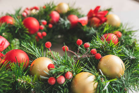 Christmas wreath decorated with red and golden balls and berries with snow, close upの写真素材