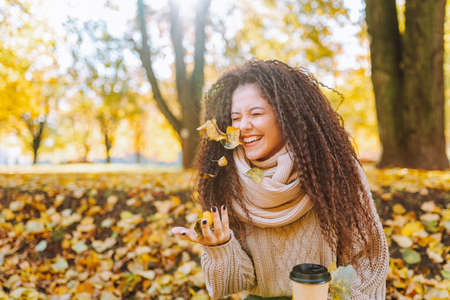 Positive afro hair woman with beautiful smile wearing knitted sweater and scarf throw yellow autumn...