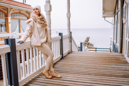 Cute middle-aged blonde woman enjoy time outdoor at winter day. Female wearing a light jacket, hat...