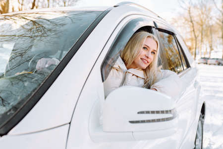 Young blonde woman sit in her new white car and smile happy. Insurance, safety, rent a carの写真素材