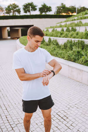 Athlete runner looking at heart rate monitor watch. Man checking his gadget before running.の写真素材