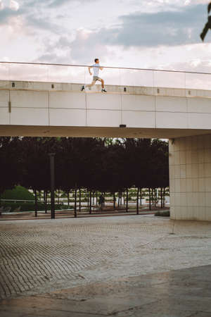 Attractive man athlete wearing sportswear run in modern park at summer dayの写真素材
